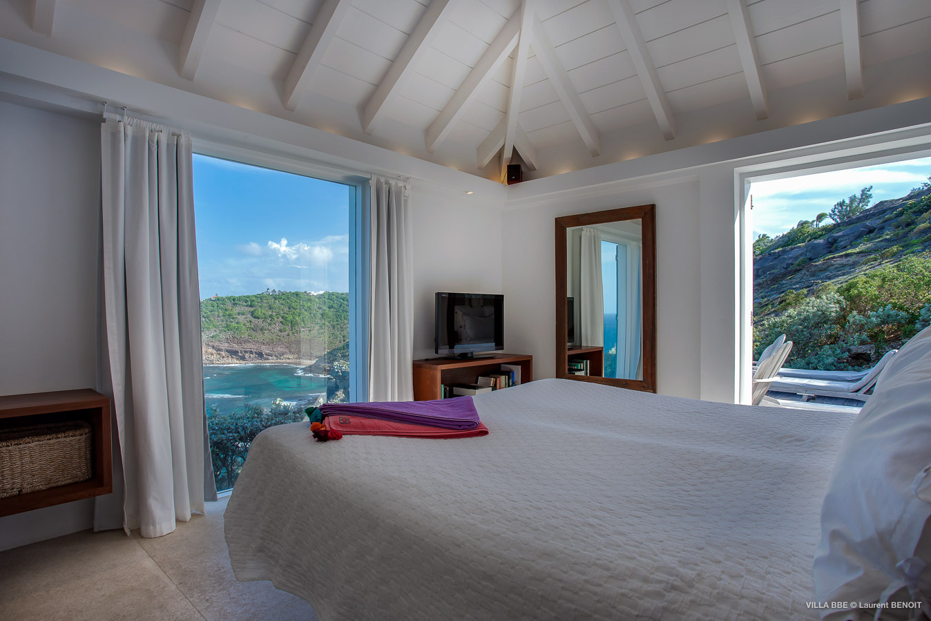 Bright bedroom with ocean views through large windows at private villa rental in St Barts
