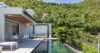 Infinity pool at St Barths villa with dining terrace and tropical hillside backdrop