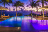 Infinity pool with glowing lights and palm trees at sunset in St Barts luxury villa rental