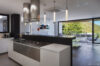 Contemporary kitchen in St Barts villa with sleek design, pendant lighting, and terrace view.
