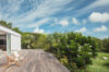 Wooden terrace of a St Barts villa with deck chairs overlooking tropical gardens and open sky
