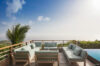 Outdoor lounge at a St Barts villa with cushioned sofas, wooden deck, and sweeping ocean views under a clear sky.