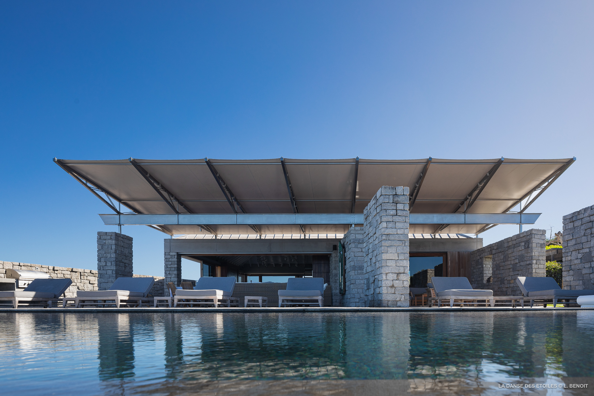 Contemporary stone St Barts villa with shaded terrace and infinity pool reflecting blue sky
