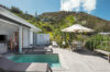 Private villa terrace in St Barts with pool, sun loungers, and shaded dining area overlooking tropical hills.