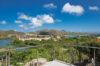 Scenic hillside and lagoon view from a St Barts villa terrace overlooking red-roofed houses and greenery