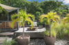 Outdoor deck of St Barts villa with potted palm trees, lounge chairs, and tropical garden view.