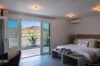 Contemporary bedroom with sliding glass doors opening to terrace and hillside view at St Barts villa rental