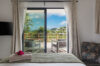 Bedroom with soft linens opening to a private terrace with hillside views in a luxury St Barts villa rental.