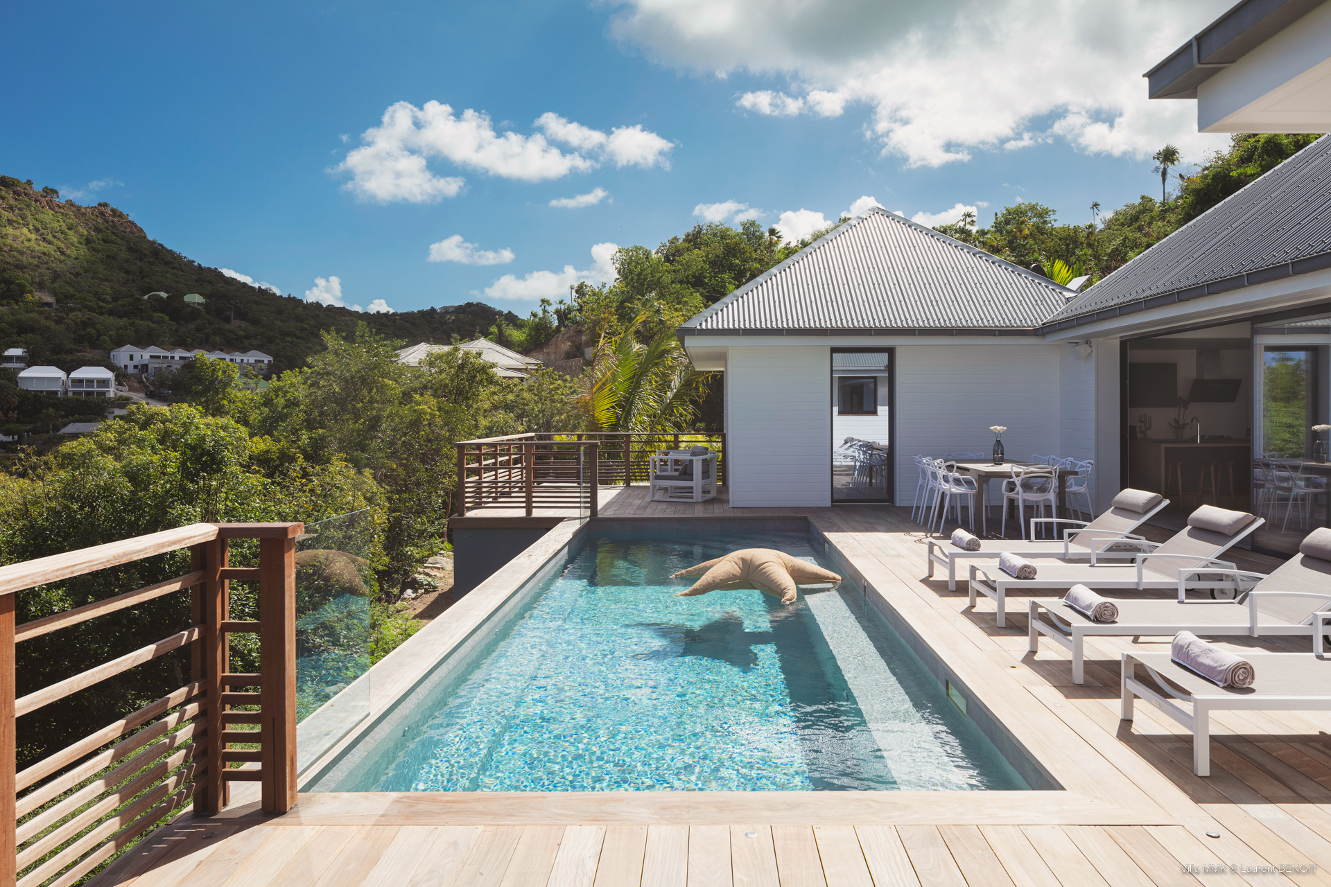 Private pool with wooden deck, sun loungers, and hillside views at a contemporary St Barts villa rental.