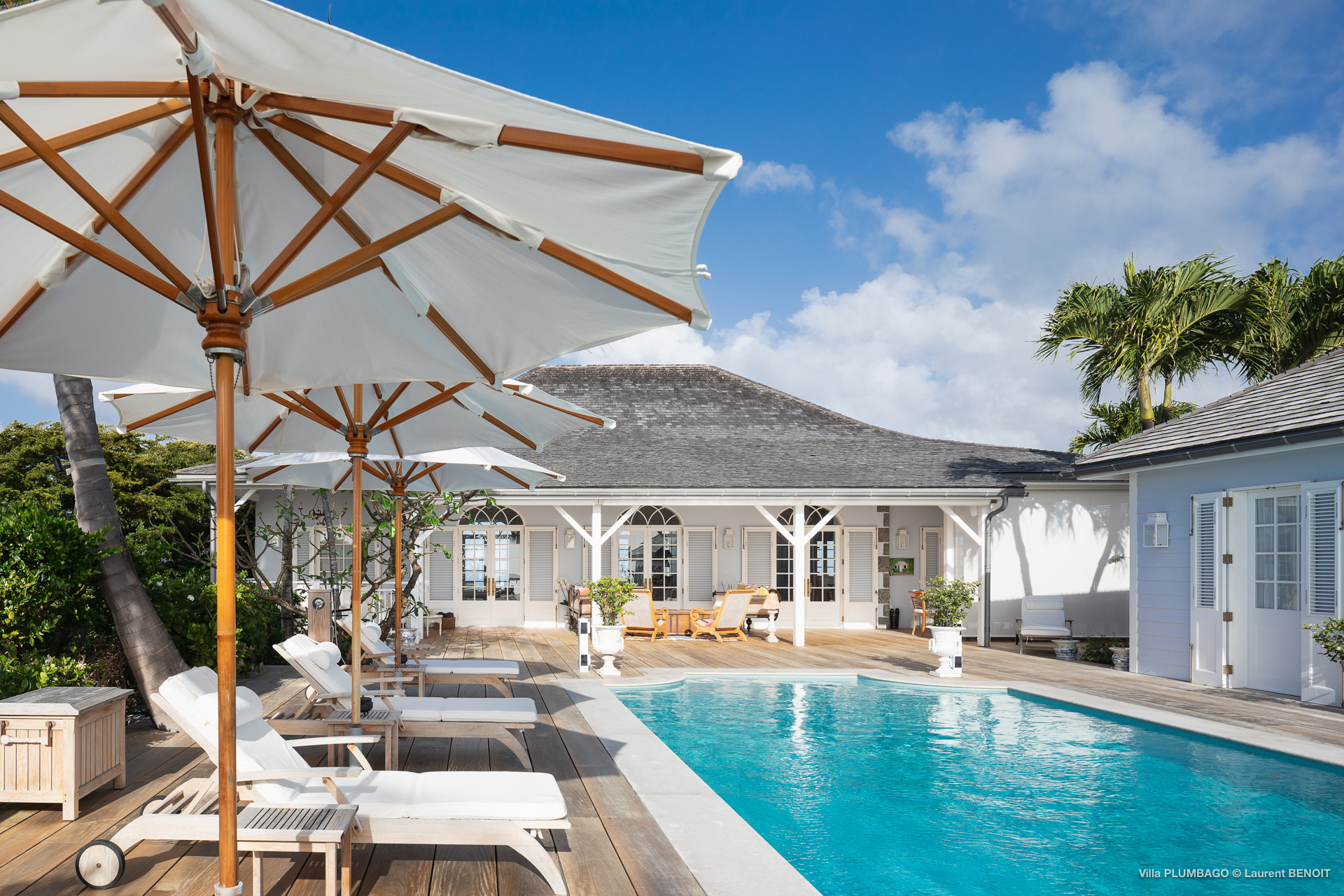 Sunny pool terrace with loungers, umbrellas, and classic Caribbean-style villa in St Barts rental