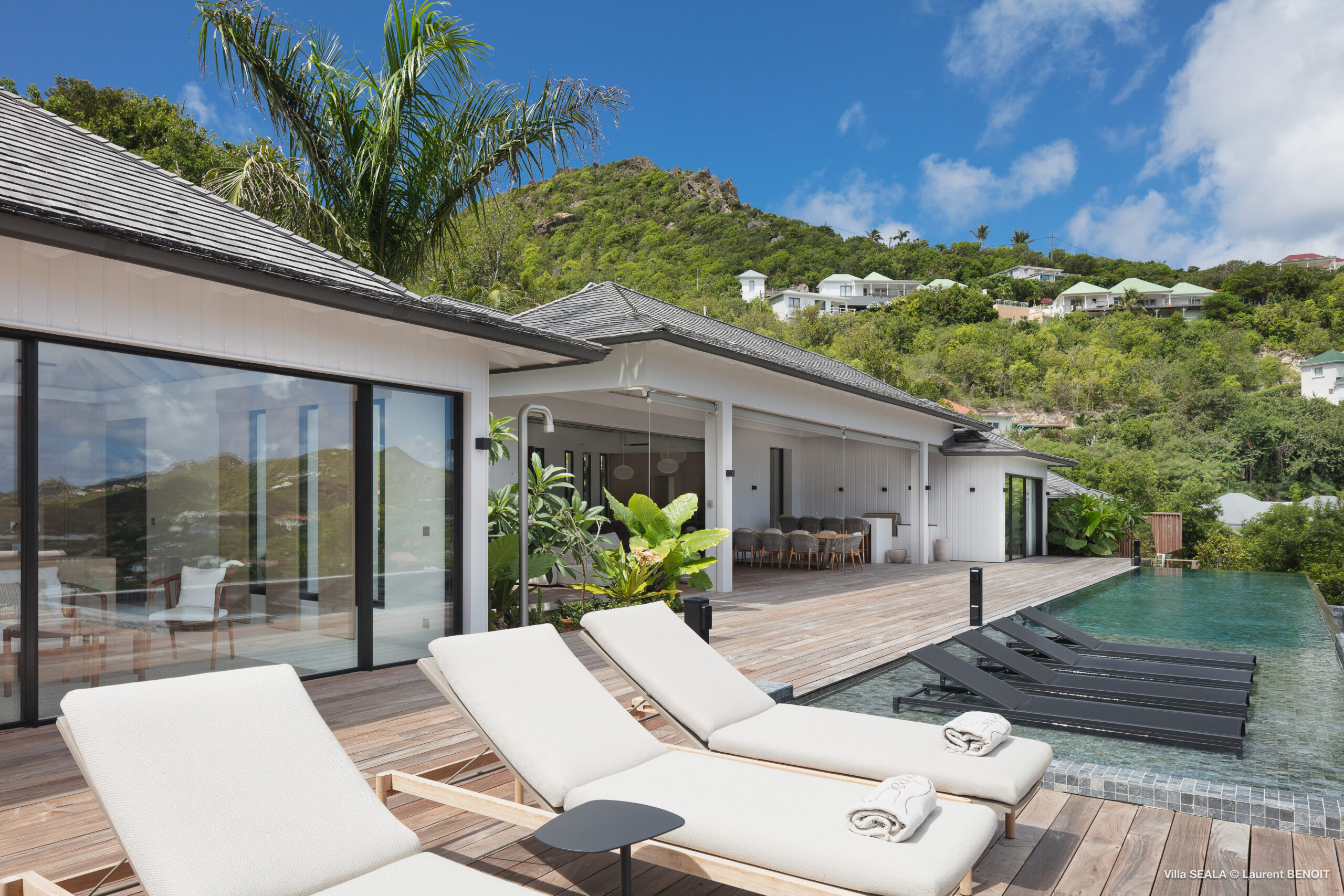 Poolside terrace with sun loungers and modern architecture at a luxury St Barts villa rental