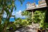 Secluded terrace of a St Barts villa with lounge chair, tropical garden and ocean view through palm trees