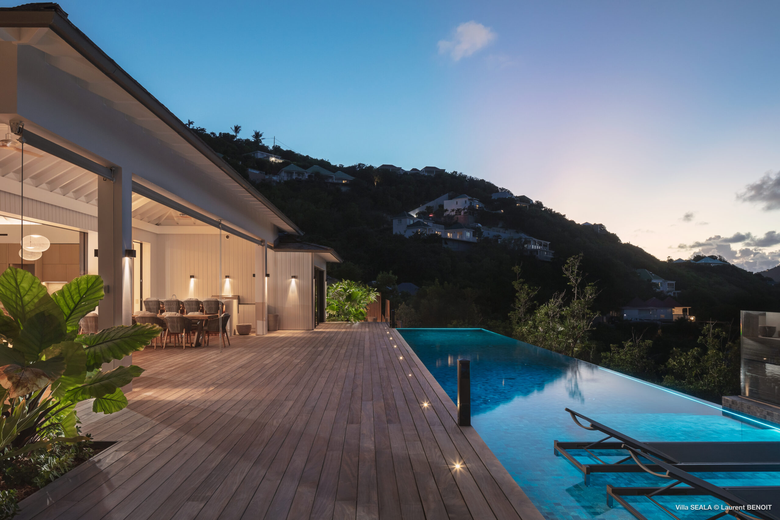 Twilight view of infinity pool and terrace with dining area at a luxury villa in St Barts