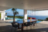 Covered terrace with pool, ocean view, and red swing chairs at St Barth villa rental