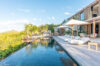 Infinity pool beside modern St Barts villa with sun loungers and hillside views