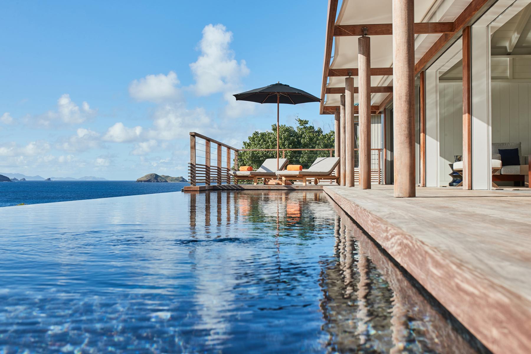 Stunning seafront infinity pool at a St. Barts villa, featuring loungers and breathtaking Caribbean panoramas.