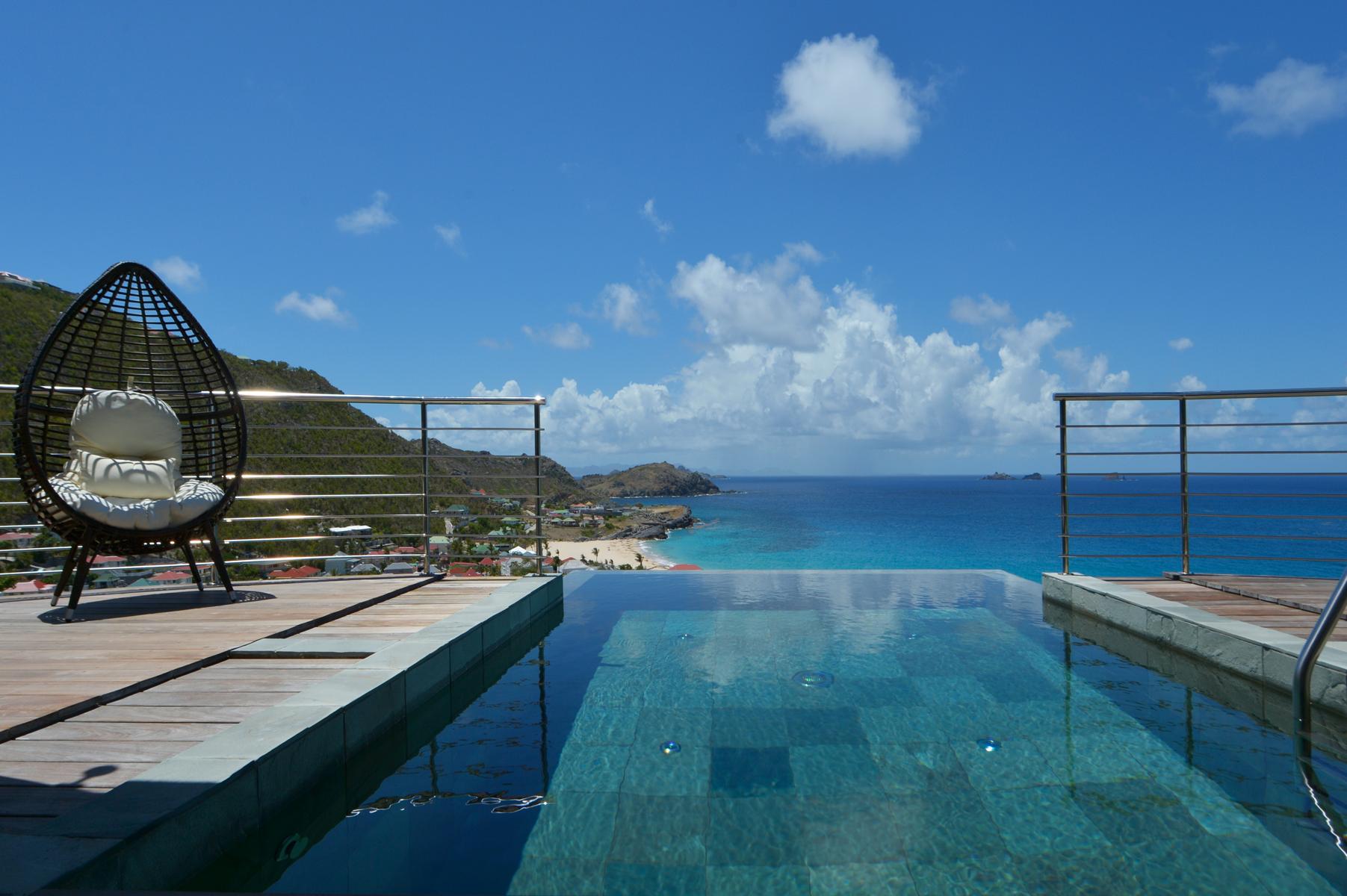 Infinity pool at St Barts villa with panoramic ocean views and modern deck seating.
