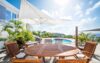 Shaded outdoor dining terrace with wooden table overlooking pool and ocean at St Barts villa rental