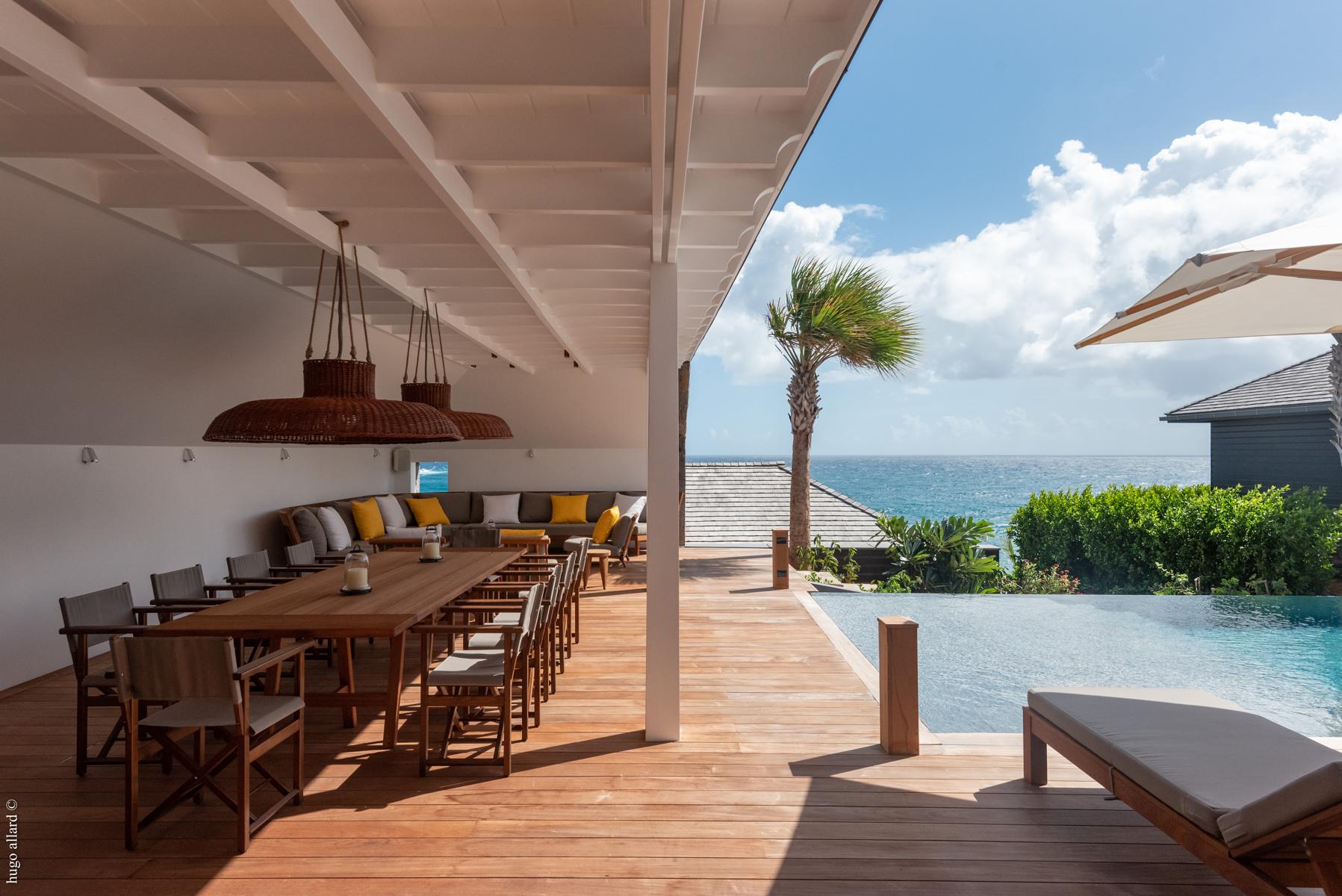 Shaded outdoor dining area beside the pool with ocean views at a luxury villa in St Barths.