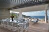 Covered outdoor dining terrace in a St Barts villa with elegant table setting, lounge chairs, and sweeping ocean views.