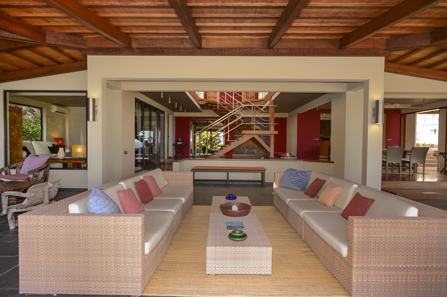 Open-air lounge in St Barts villas with rattan sofas and view of modern staircase