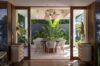 Elegant dining area in a St Barts villa with tropical greenery backdrop and modern woven chairs.