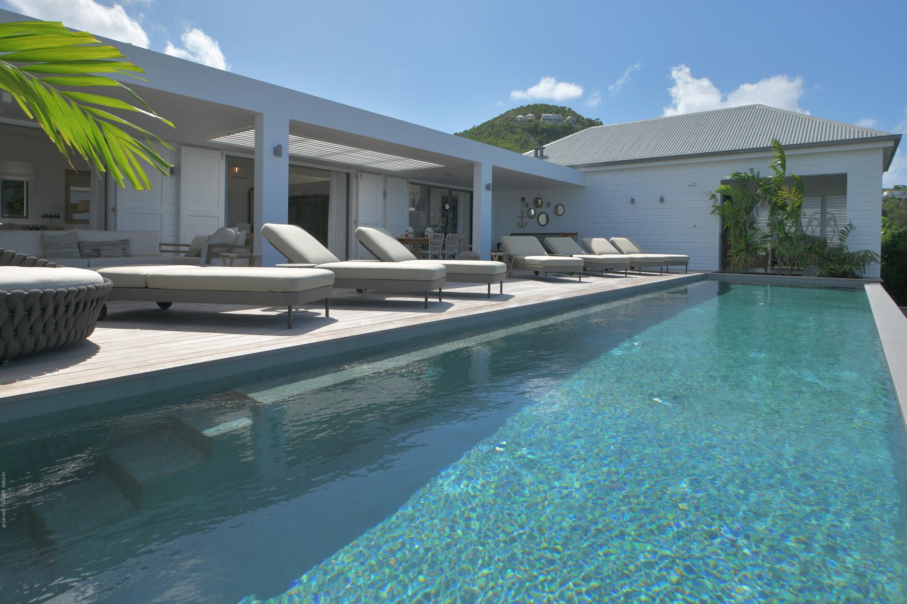 Modern St Barts villa with long swimming pool, sun loungers, and shaded terrace areas
