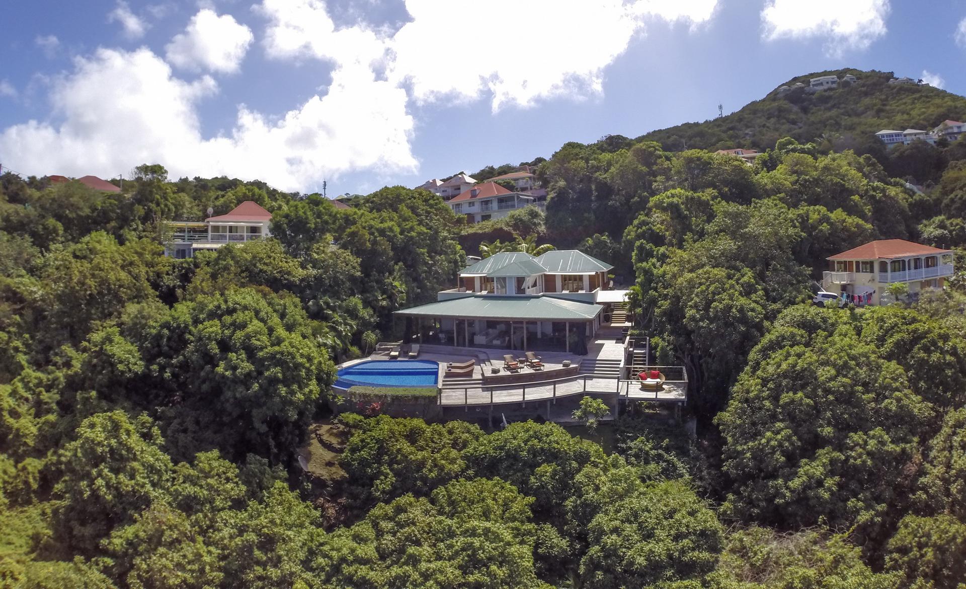 Aerial view of luxury villas St Barts surrounded by lush hills and infinity pool