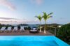 Infinity pool at a St Barts villa with sun loungers, circular daybed, and sunset views over the Caribbean Sea and islands.