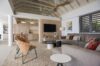 Stylish living room in a St Barts villa with modern décor, cozy sectional sofa, and open-plan kitchen under vaulted ceilings.