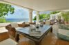 Covered outdoor lounge at a St Barts villa with wicker seating, ocean views, and elegant dining and relaxation spaces.