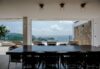 Covered dining area in a St Barts villa with sleek black chairs, large wooden table, and ocean views beyond the terrace.
