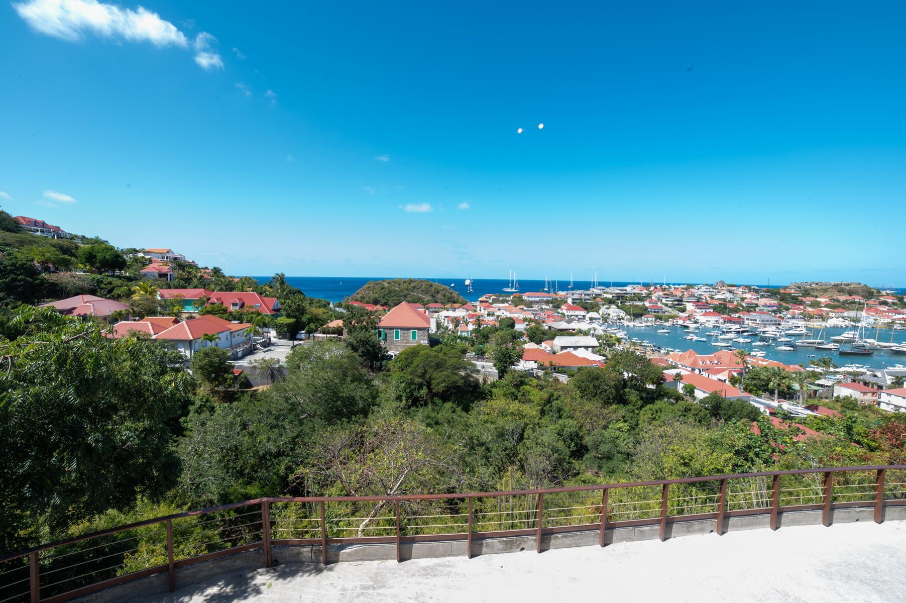 Panoramic view of Gustavia harbor from a hillside St Barts villa overlooking red-roofed houses and the sea