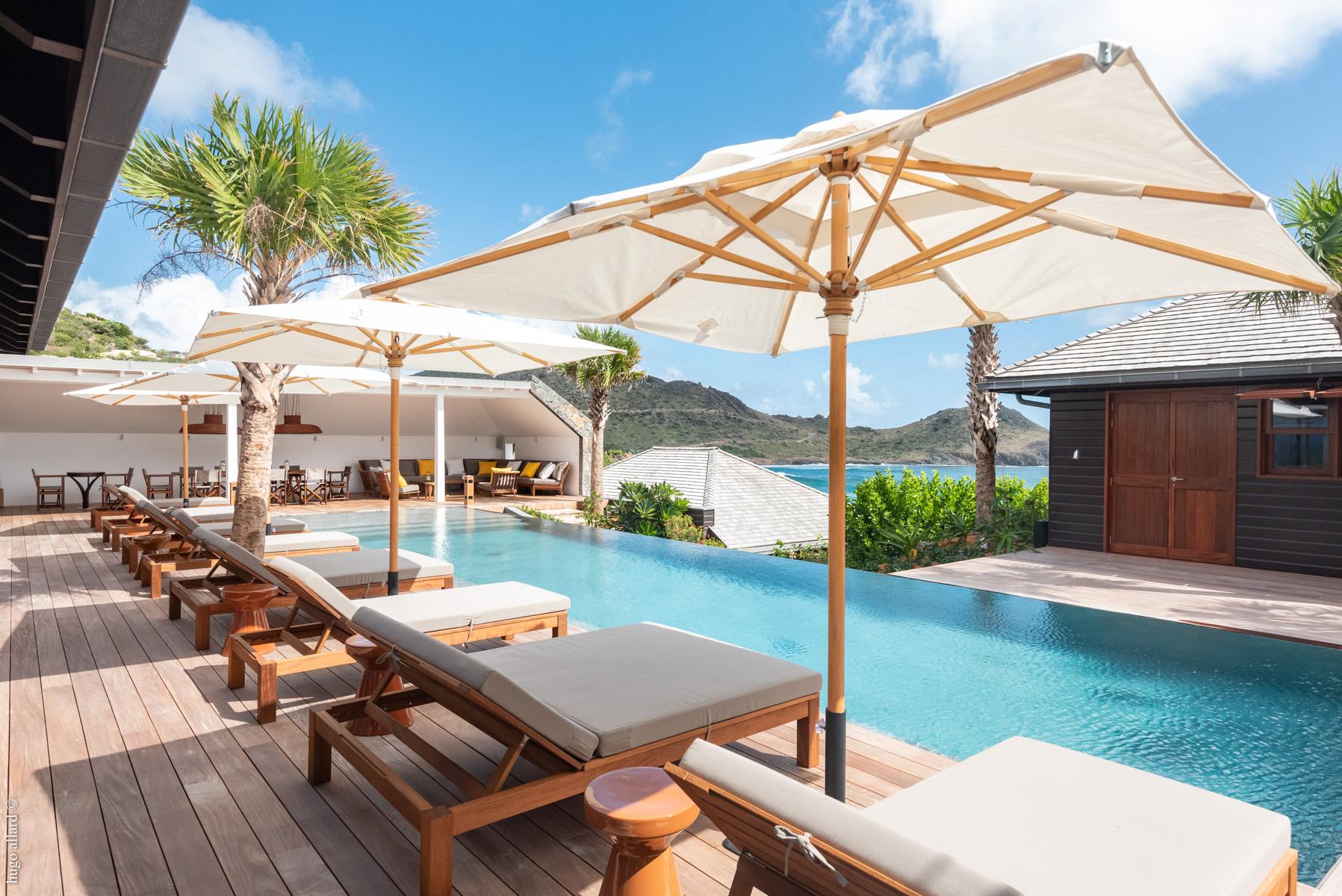 Sun loungers shaded by umbrellas beside the pool at a luxury villa in St Barths.