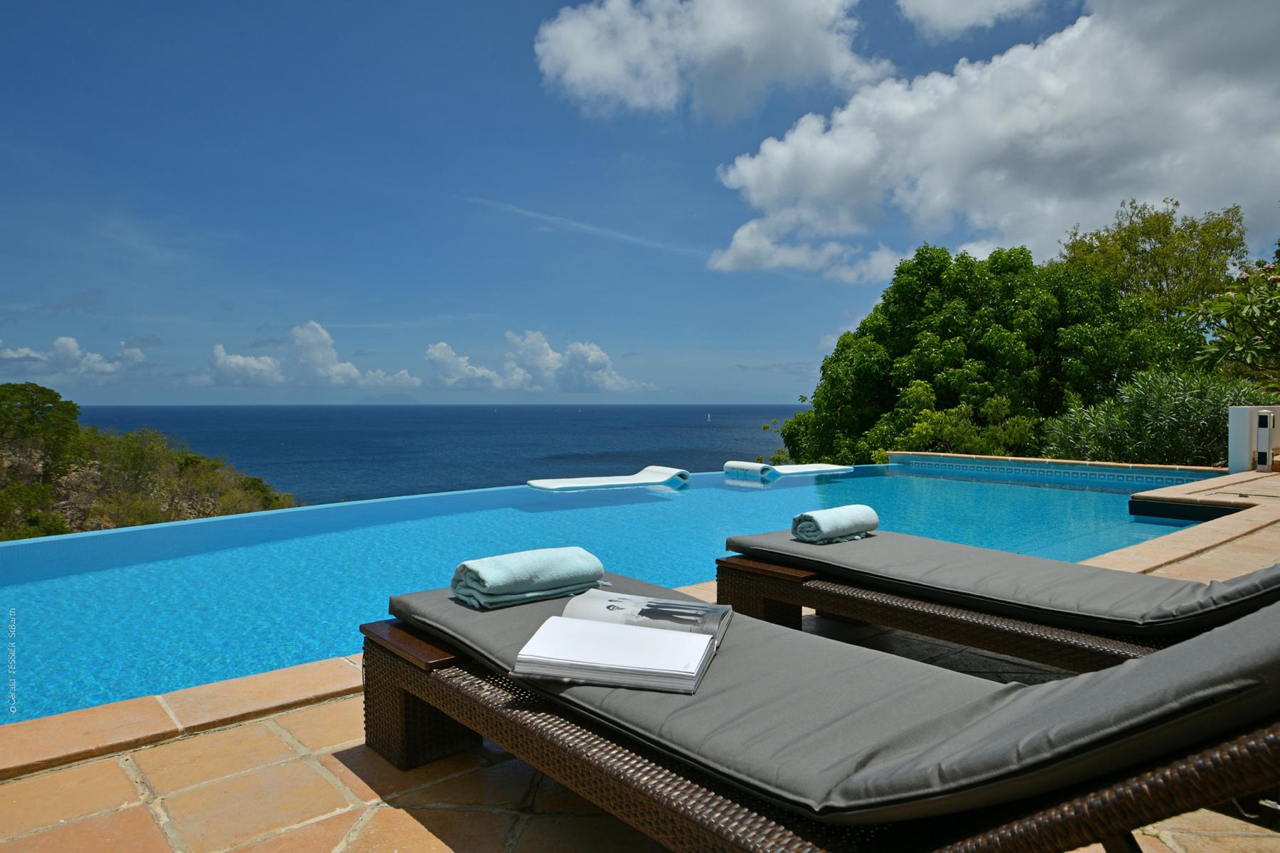 Infinity pool at St Barts villa with sun loungers overlooking the Caribbean Sea