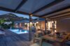 Evening ambiance at a St Barts villa with poolside terrace, alfresco dining table, and warm lighting against hillside views.
