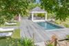 Tropical garden pathway leading to a pool at a St Barts villa, with sun loungers, palm trees, and distant ocean views.