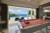 Entertainment room in a St Barts villa with red pool table, bar setup, and open view of the infinity pool and ocean