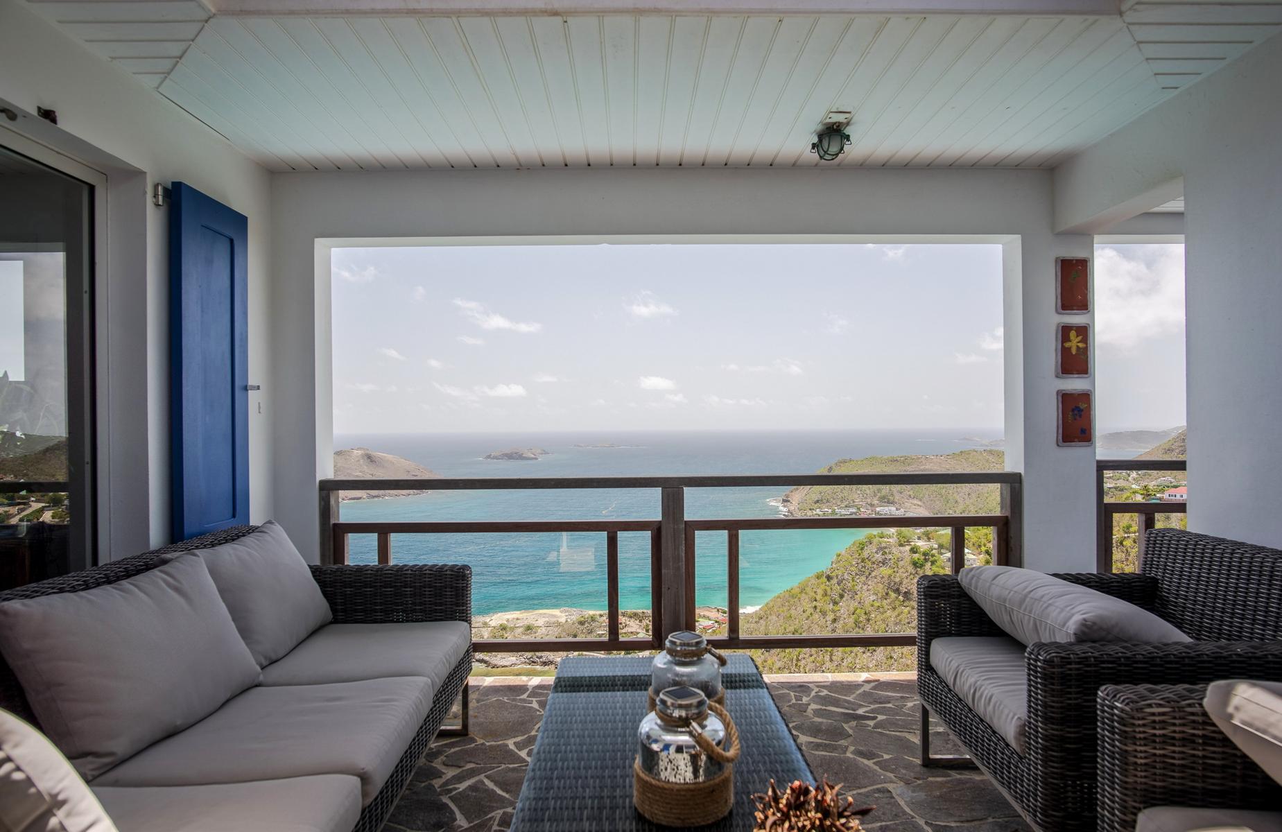 Covered terrace with wicker sofas and panoramic ocean views at St Barthelemy villa rental