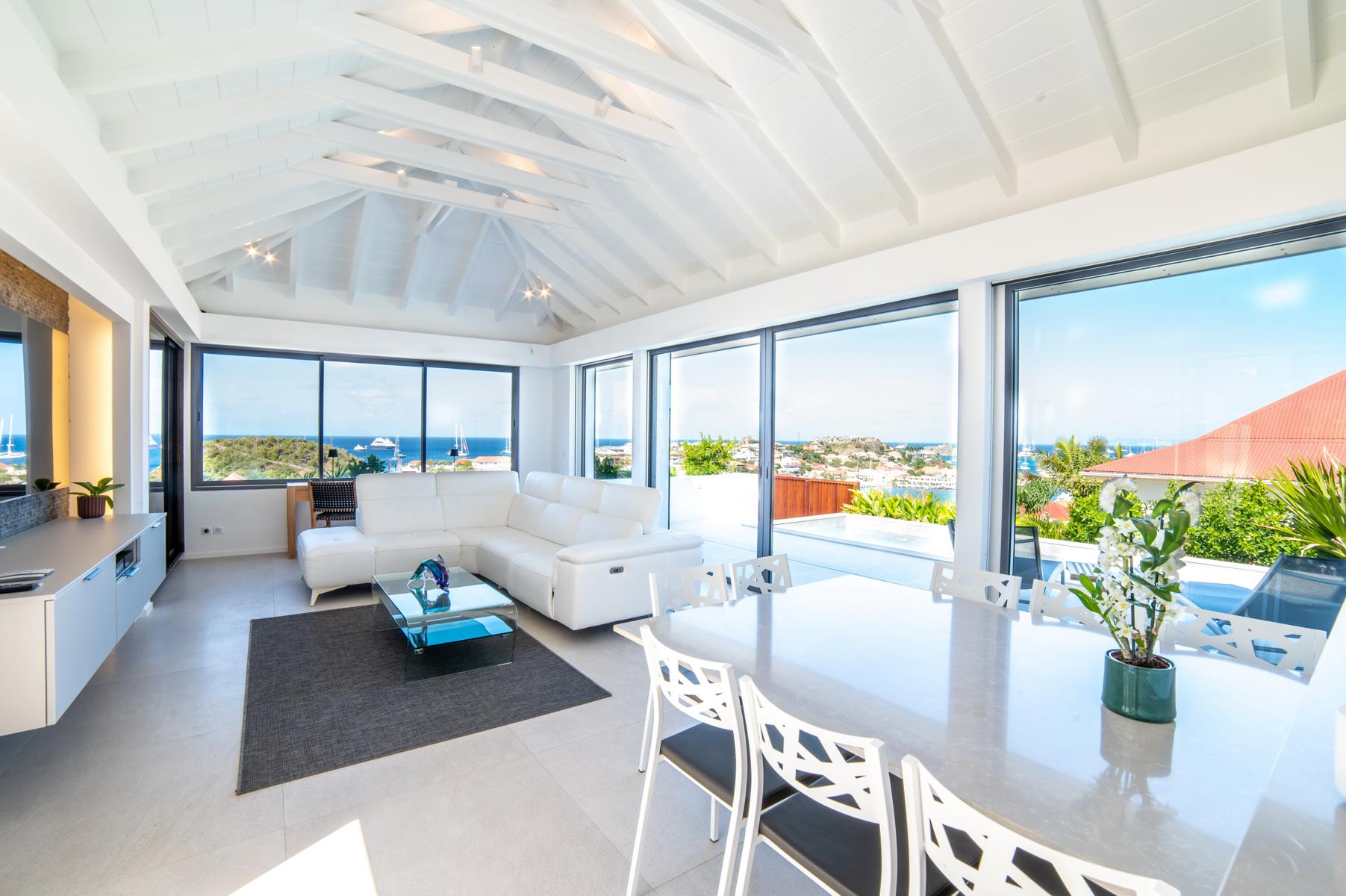 Bright open-plan living and dining area in a St Barts villa with sea views through panoramic windows