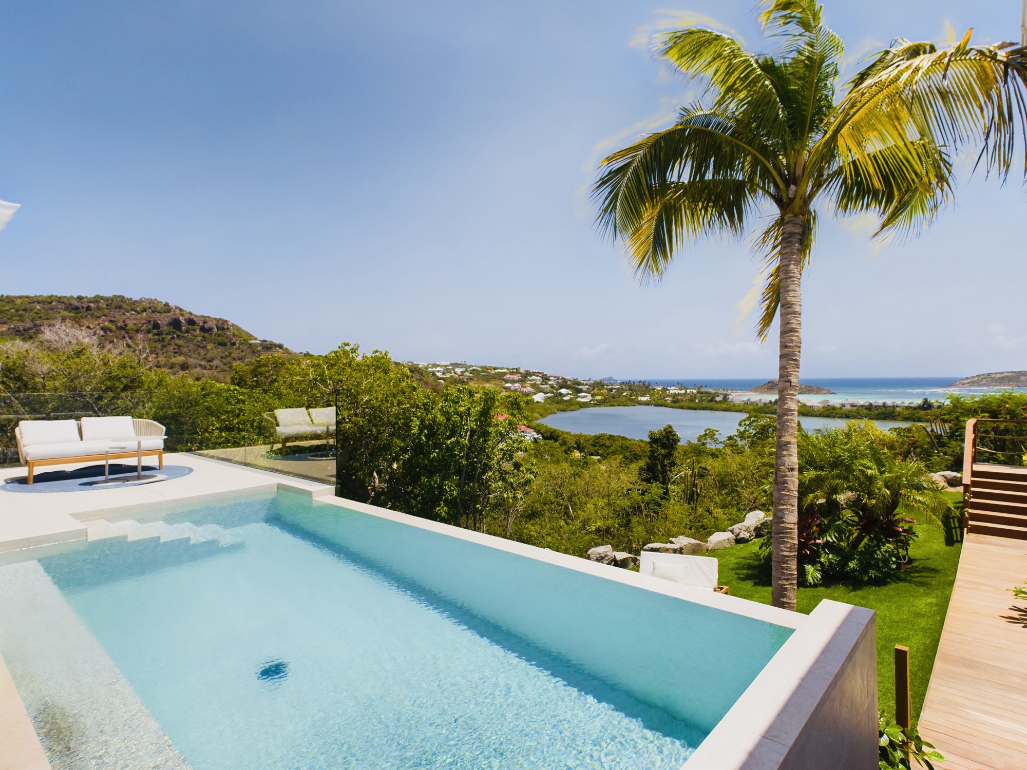 Infinity-edge pool at a St Barts vacation rental with palm tree and panoramic bay views.