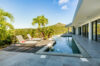 Elegant St Barts villa with poolside deck, sun loungers, and tropical palm views against the backdrop of green hills