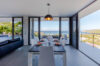 Dining room in a St Barts villa with floor-to-ceiling glass walls, set table, and panoramic Caribbean Sea views.