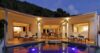 Evening view of luxury St Barts villa with illuminated pool, lounge chairs, and open-air living spaces