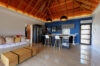 Open-plan villa interior with cozy sofa, modern kitchen, and vaulted wooden ceiling in St Barts.