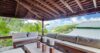 Covered outdoor lounge with cushioned sofas, wooden beams, and hillside views at St Barts villa rental