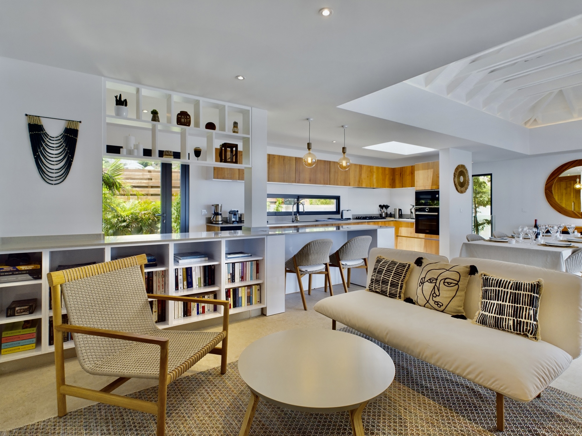 Bright open-plan living room with modern kitchen, cozy seating, and natural accents in a St Barts villa rental.