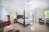 Elegant bedroom in St Barts villas with four-poster bed and bright natural light