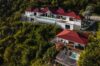 A hillside St Barts villa with red rooftops, infinity pool, and panoramic ocean views surrounded by lush greenery.