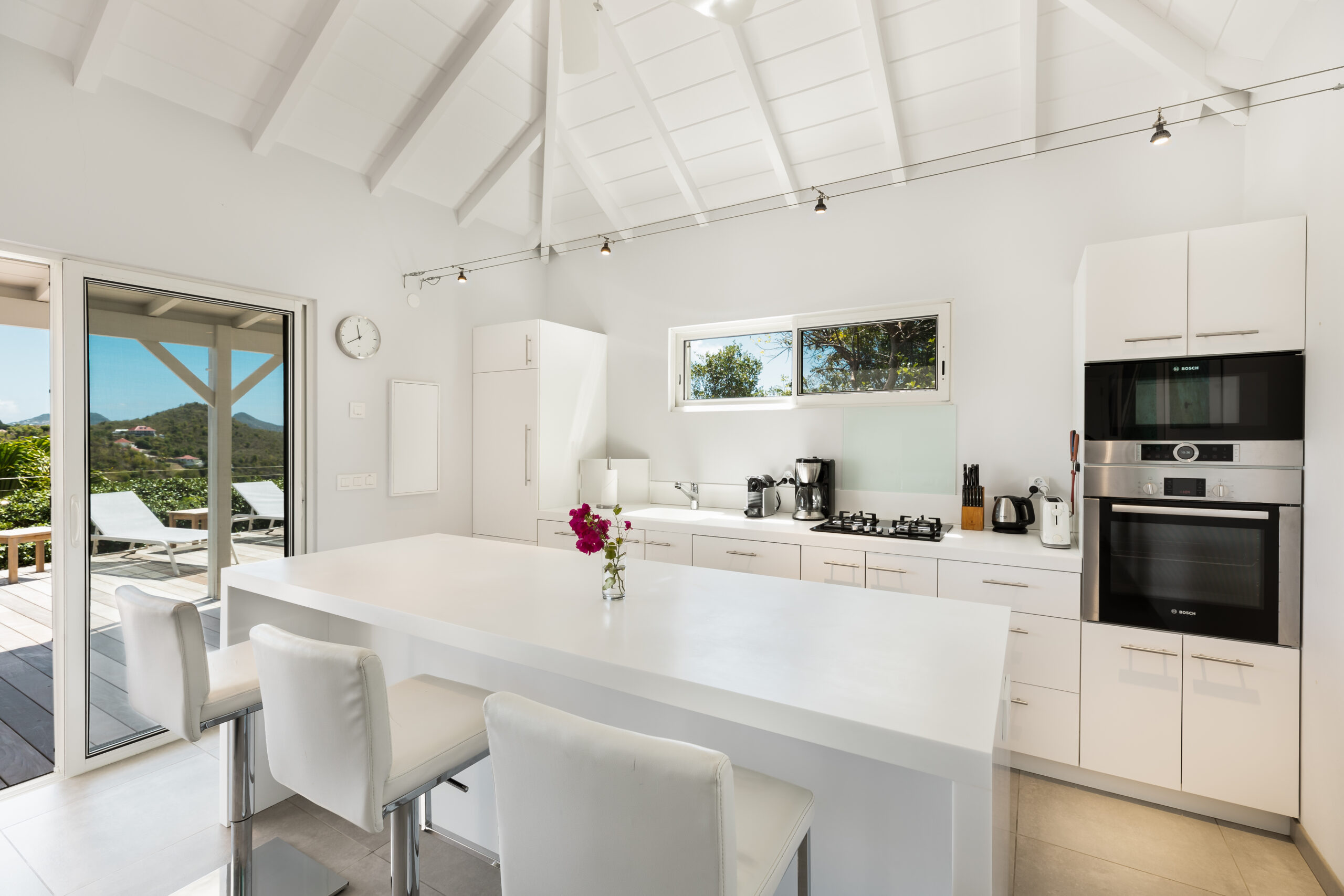Bright kitchen in St Barts villa rentals with white island and terrace access